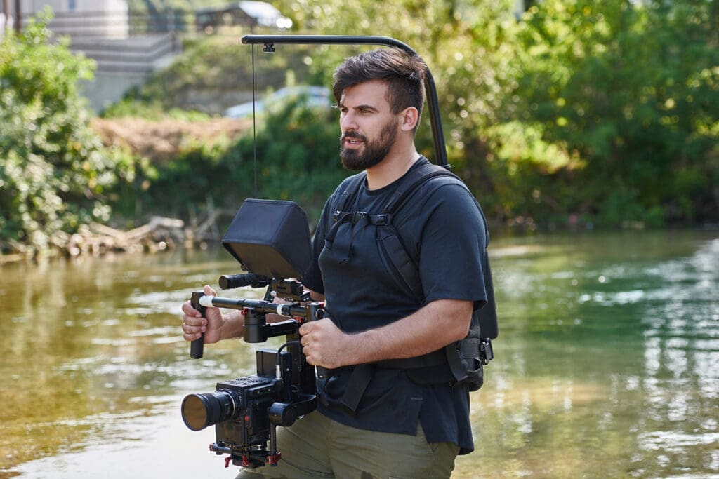 a professionally equipped cameraman shoots in the water surrounded by beautiful nature